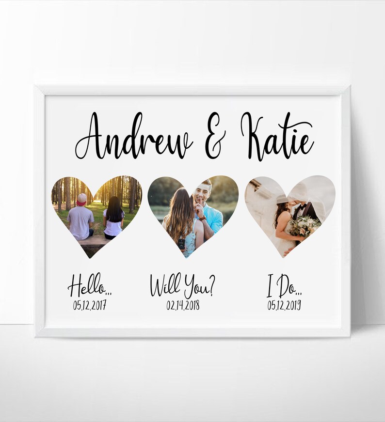 K&ouml;nnte beinhalten: Ein wei&szlig; gerahmter Druck mit drei herzf&ouml;rmigen Fotoausschnitten. Oben auf dem Druck steht "Andrew & Katie" in Schreibschrift. Unter den Fotos stehen die S&auml;tze "Hello...", "Will You?" und "I Do..." mit Daten.