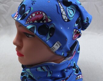 May include: Blue beanie and neck warmer set with a cartoon character print. The character has blue skin, large eyes, and a toothy grin. The set is made of soft, comfortable fabric.