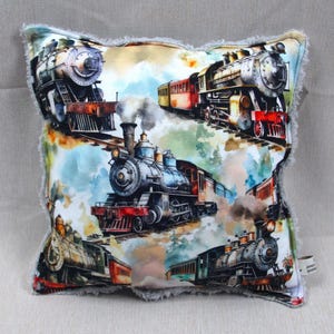 May include: A decorative pillow with a white background and a repeating pattern of vintage steam locomotives. The locomotives are depicted in a watercolor style with shades of blue, red, green, and brown. The pillow has a fluffy, gray border.