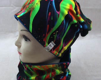 May include: A black beanie and neck warmer set with a colorful abstract print. The print features bright green, yellow, orange, red, and blue colors. The beanie has a fold-over cuff and the neck warmer is a tube style.