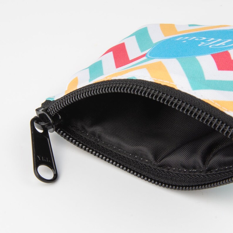 May include: A small zippered pouch with a colorful chevron pattern. The pouch is made of fabric and has a black zipper. The pouch is open and the inside is black.