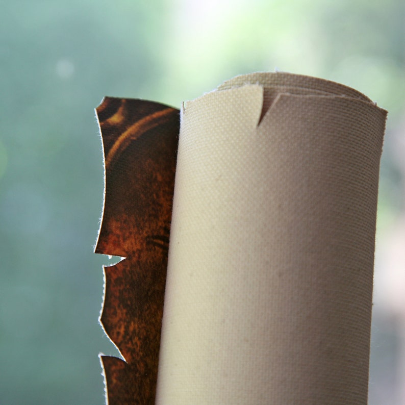 Pu&ograve; includere: Un primo piano di un dipinto su tela arrotolato con una cornice marrone e dorata. La tela &egrave; bianca e la cornice &egrave; parzialmente visibile.