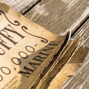 May include: Close-up of a stack of brown paper with the text "OFFY" and "00-000-0" printed in black. The text "MARINE" is printed in black on the top sheet of paper.