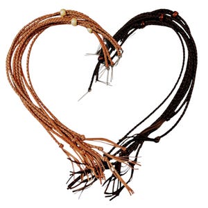May include: A set of brown and black leather cords with wooden beads and tassels. The cords are arranged in a heart shape.