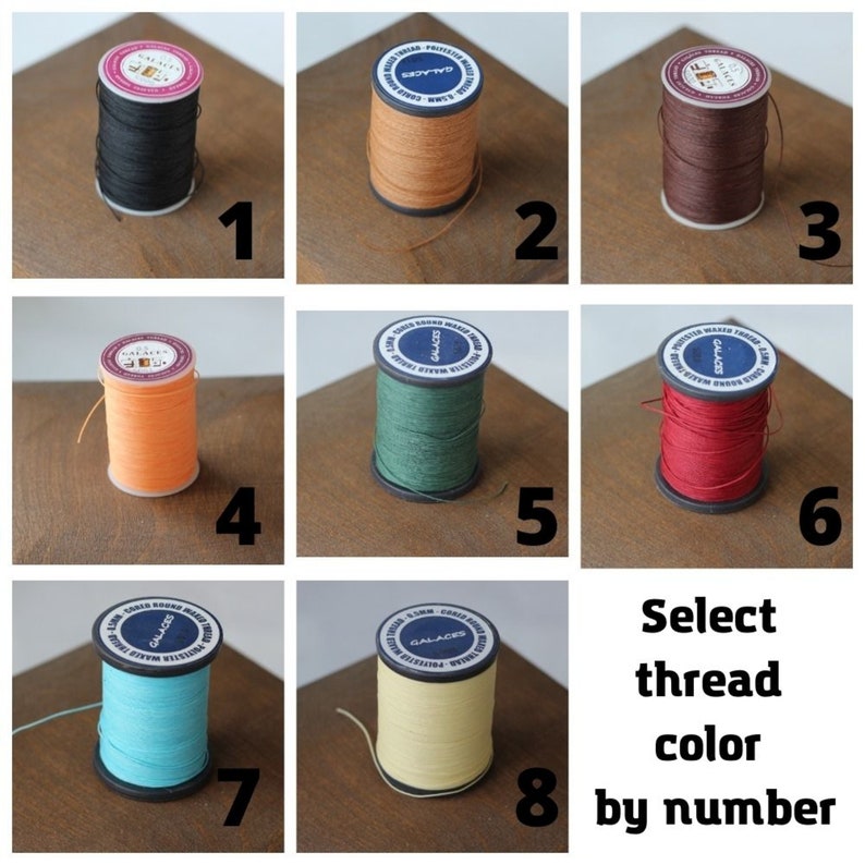 May include: A collection of eight spools of thread in various colors, including black, orange, green, and red. Each spool is labeled with a number from 1 to 8. The text "Select thread color by number" is also present.