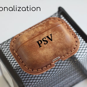 May include: A brown leather case for AirPods with the initials "PSV" embossed on the front.