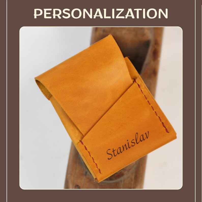 May include: A handcrafted, open leather cardholder in a warm, golden-brown hue. The cardholder features a stitched edge with red thread and the name "Stanislav" engraved on the front. The word "PERSONALIZATION" is at the top.