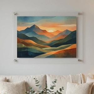 May include: A rectangular landscape wall art piece featuring a stylized mountain range at sunset with layered hues of blue, orange, and gold. The artwork is mounted behind a clear acrylic panel secured with four silver metal standoffs at the corners.