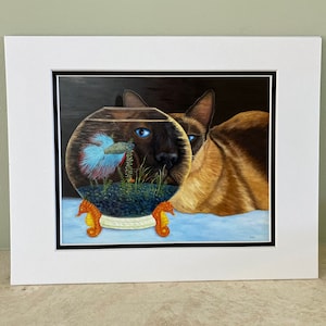 May include: A framed painting of a Siamese cat looking at a fishbowl with a blue and red betta fish inside. The fishbowl is on a stand with two orange seahorse figurines.