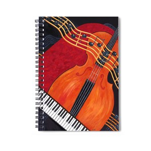 May include: A spiral bound notebook with a colorful illustration of a cello and a piano keyboard. The cello is orange and red with black strings. The piano keyboard is black and white. Musical notes are drawn in yellow on a black background.