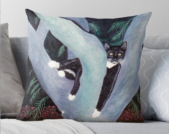 May include: Decorative throw pillow featuring a black and white cat perched in a tree. The cat has yellow eyes and white paws. The background includes blue and green foliage and red berries.