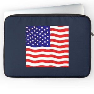 May include: A navy blue laptop sleeve featuring the American flag. The flag design includes a blue field with white stars and red and white stripes. The sleeve has a black zipper and a white laptop peeking out.