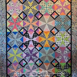 May include: A colorful quilt with a geometric starburst pattern. The quilt features squares with various designs, including stripes, polka dots, and floral patterns. The color palette includes pink, orange, yellow, blue, and green, with a black border.