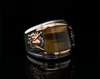 May include: A silver ring with a tiger's eye stone and a detailed design on the band.