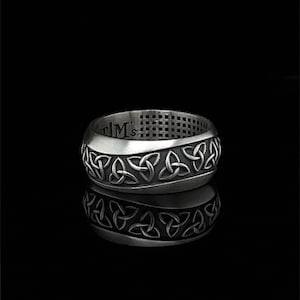 May include: A silver ring with a Celtic knot design. The ring is engraved with the text "TIM's".