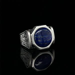 以下が含まれることがあります： 装飾的なバンドにセットされた八角形のラピスラズリ石が付いた銀のリングです。