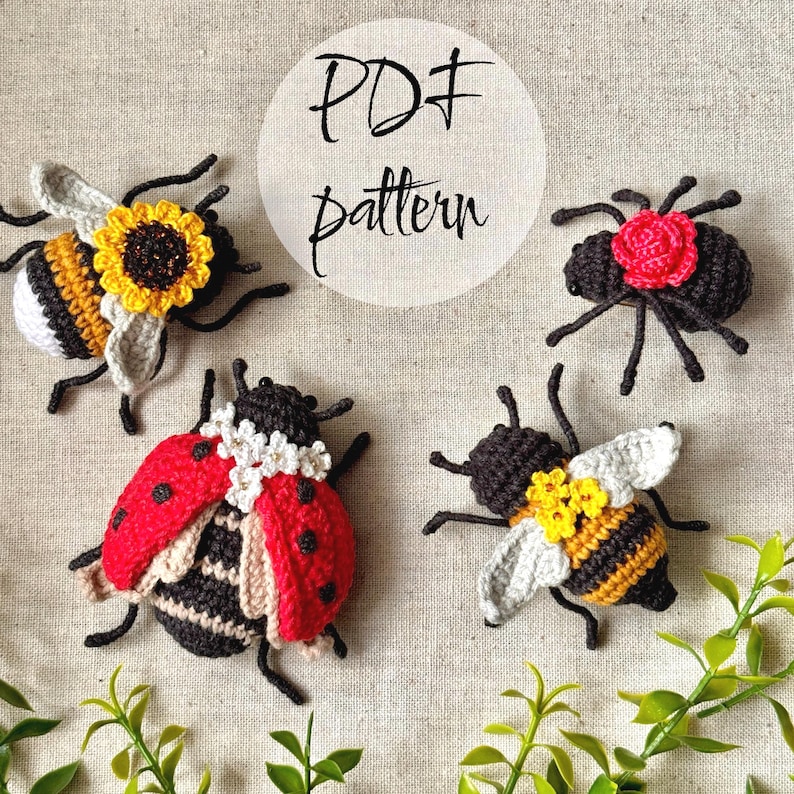 May include: Four crocheted insect figures including a ladybug with white flowers, a bee with a sunflower, a bee with yellow flowers, and a black beetle with a red rose. The text PDF pattern is centred above the figures on a light fabric background.