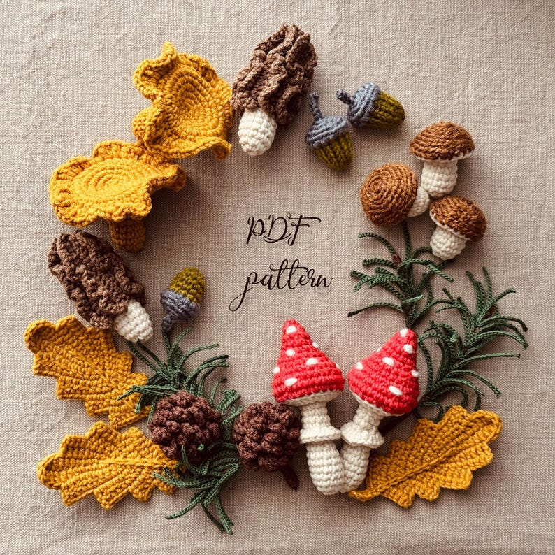 May include: A circular arrangement of crocheted autumn-themed items. Includes yellow leaves, brown mushrooms, red mushrooms with white spots, acorns, and pinecones. The text "PDF pattern" is in the center. The items are arranged on a neutral-colored surface.