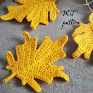 Puede incluir: Primer plano de varios adornos de hojas de arce amarillas de ganchillo. Las hojas están hechas con una puntada texturizada y tienen bordes detallados. El texto "PDF pattern" es visible en la esquina superior derecha.