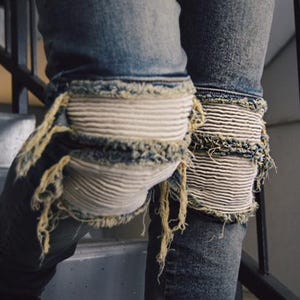 May include: Blue denim jeans with white knee patches and frayed edges.