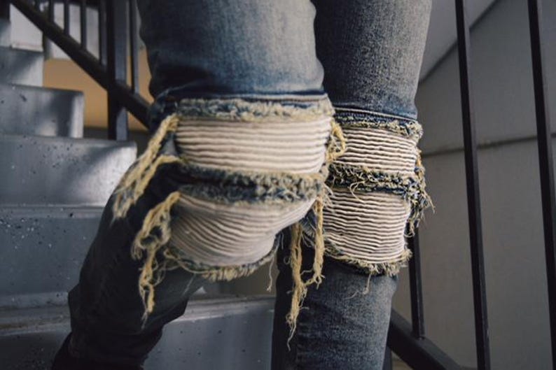 May include: Blue denim jeans with white knee patches and frayed edges.