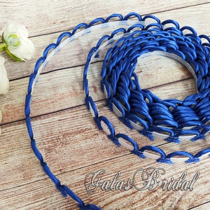May include: Blue satin trim with scalloped edges. The trim is rolled into a circle and is approximately 1 inch wide. The trim is perfect for adding a touch of elegance to any project.