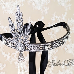 May include: A silver and black headband with a pearl and crystal design. The headband has a black ribbon tie and a dangling pearl and crystal tassel.