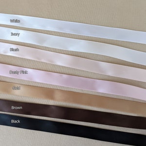 May include: A selection of satin ribbon in various colors, including white, ivory, blush, dusty pink, gold, brown, and black.