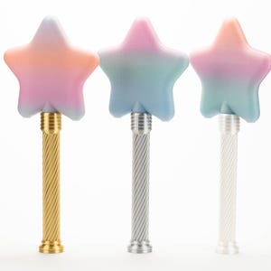 Peut inclure: Trois baguettes magiques en forme d'&eacute;toile aux couleurs d&eacute;grad&eacute;es. Les baguettes ont un manche en m&eacute;tal torsad&eacute; dor&eacute;, argent&eacute; et blanc. Les couleurs des &eacute;toiles sont rose, bleu et orange. Les baguettes sont sur fond blanc.