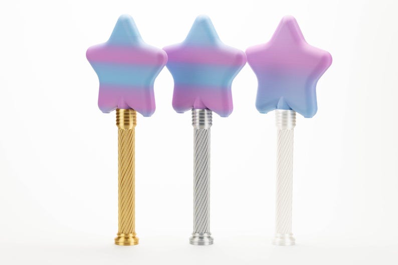 Peut inclure: Trois baguettes en forme d'&eacute;toile avec des d&eacute;grad&eacute;s de couleurs pastel bleu, violet et rose. Les baguettes ont des manches en m&eacute;tal torsad&eacute; en or, argent et blanc. Les baguettes sont sur fond blanc.