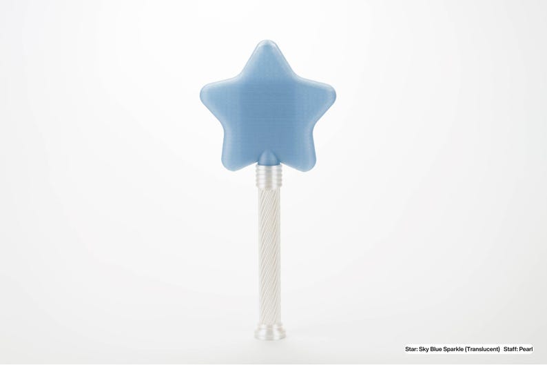 Peut inclure: Une baguette en forme d'&eacute;toile bleu ciel avec un manche perl&eacute;. L'&eacute;toile est de couleur bleu translucide. Le manche est argent&eacute; avec un motif torsad&eacute;. Le texte en bas indique : Star: Sky Blue Sparkle (Translucent) Staff: Pearl.