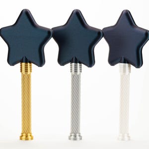 Peut inclure: Trois bouchons de bouteille en forme d'&eacute;toile avec des dessus bleu fonc&eacute; et des tiges textur&eacute;es. Un bouchon a une tige dor&eacute;e, un est argent&eacute; et le troisi&egrave;me est blanc. Les bouchons sont dispos&eacute;s sur un fond blanc.
