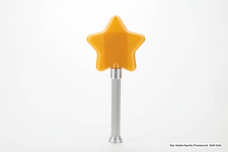 Peut inclure: Une baguette dor&eacute;e en forme d'&eacute;toile avec un manche torsad&eacute; argent&eacute;. L'&eacute;toile est translucide et a une surface textur&eacute;e. La baguette est pos&eacute;e sur un fond blanc. Le texte en bas indique "Star: Golden Sparkle (Translucent) Staff: Gold".