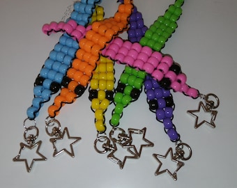 Può includere: Una collezione di braccialetti colorati con perline blu, arancioni, gialli, verdi, rosa e viola. Ogni braccialetto ha un ciondolo a forma di stella. I braccialetti sono fatti di piccole perline rotonde.