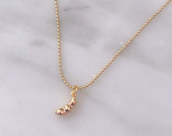 May include: A gold chain necklace with a small gold pea pod pendant.