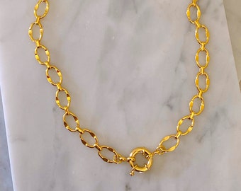 May include: A gold chain necklace with a toggle clasp. The chain is made of oval links.