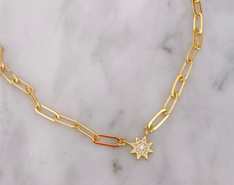 May include: A gold chain necklace with a small, sparkly star pendant.