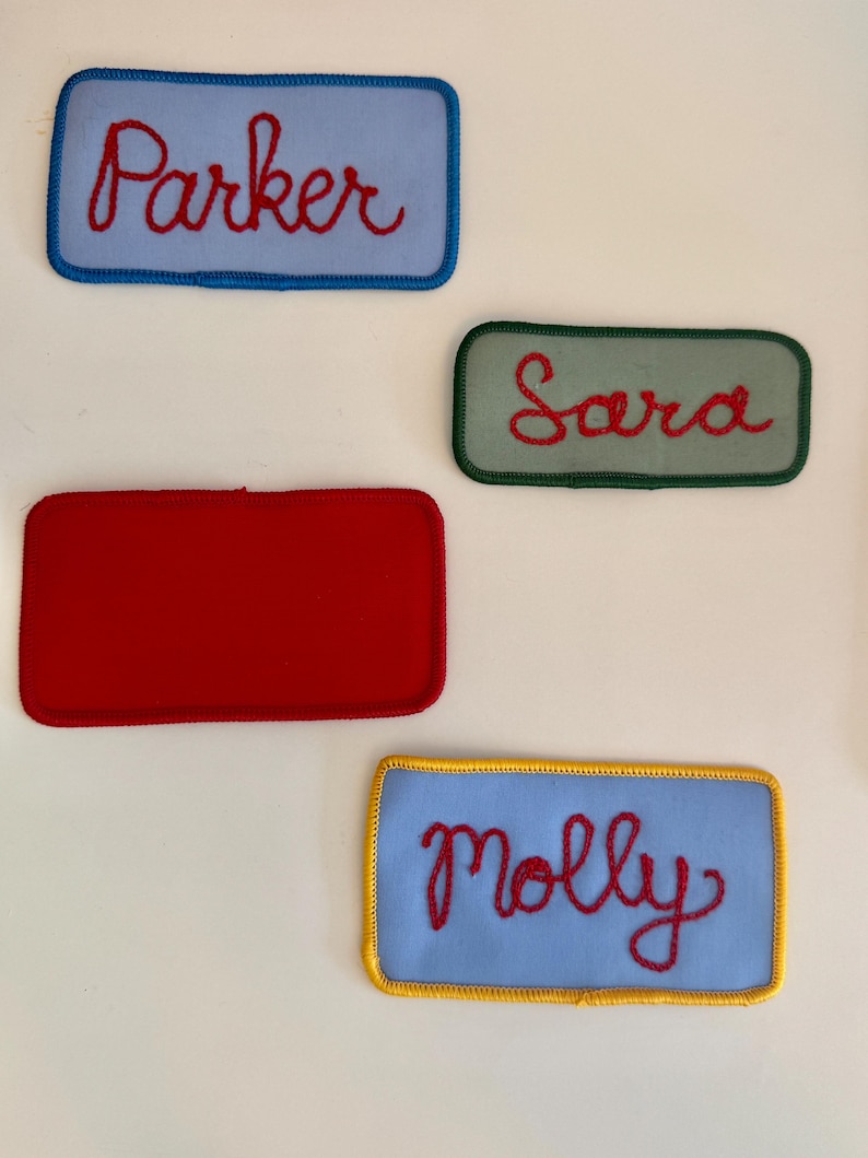 Pode incluir: Quatro patches de nome bordados. Os patches s&atilde;o retangulares com cantos arredondados. Os nomes "Parker" e "Molly" est&atilde;o em patches azul claro, "Sara" est&aacute; em um patch verde e um patch vermelho est&aacute; em branco. Os nomes est&atilde;o em it&aacute;lico vermelho.