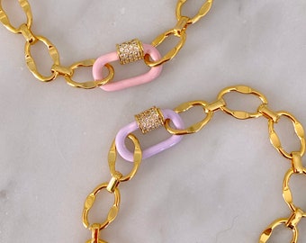 May include: Two gold chain bracelets with a pink and a lavender enamel clasp. Each clasp is accented with clear rhinestones.