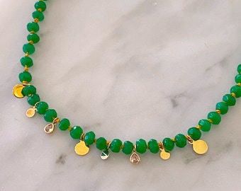 May include: A green glass bead necklace with gold and clear crystal accents. The necklace features small, round gold charms and clear crystal drops.