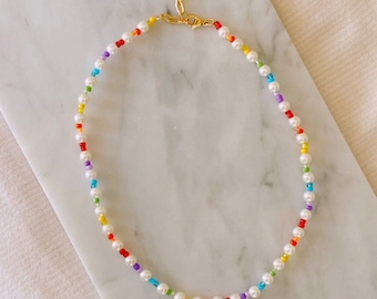 May include: A delicate rainbow beaded necklace with white pearls and a gold clasp.