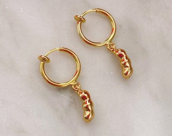 May include: A pair of gold hoop earrings with a dangling charm. The charm is a cluster of small, rounded shapes.