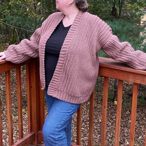 May include: A mauve cardigan with a relaxed fit and long sleeves. The cardigan is open in the front and has a ribbed texture.