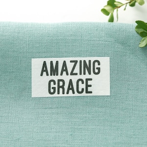 May include: A light blue fabric with a white label that says "AMAZING GRACE" in black text.