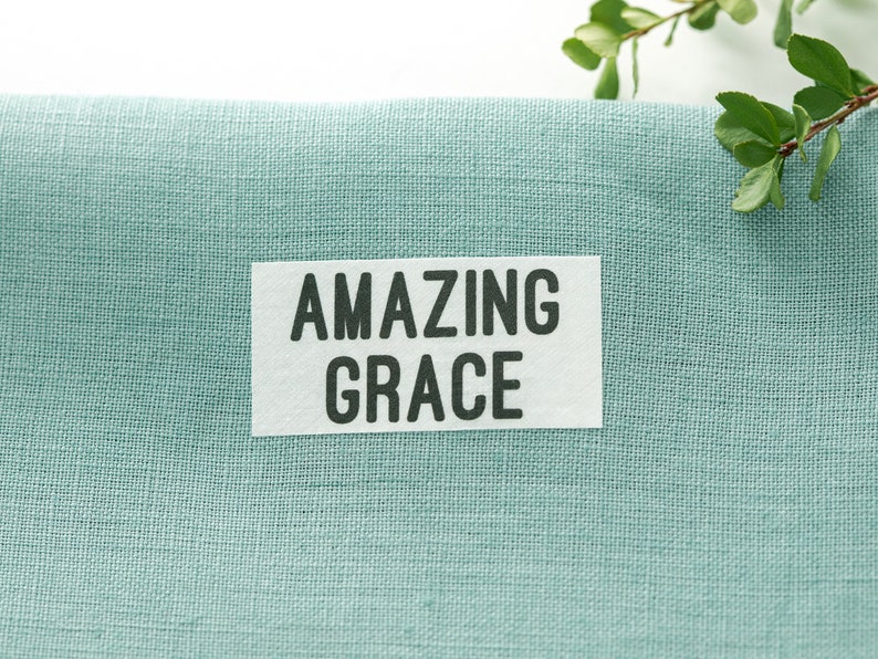 May include: A light blue fabric with a white label that says "AMAZING GRACE" in black text.