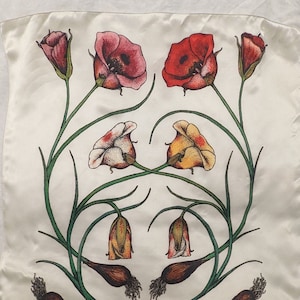 Op de afbeelding: Vierkante, crèmekleurige zijden sjaal met een bloemenontwerp. Het ontwerp toont rode, roze en gele bloemen met groene stelen en bladeren. De bloemen zijn symmetrisch gerangschikt, sommige in volle bloei en andere als knoppen.