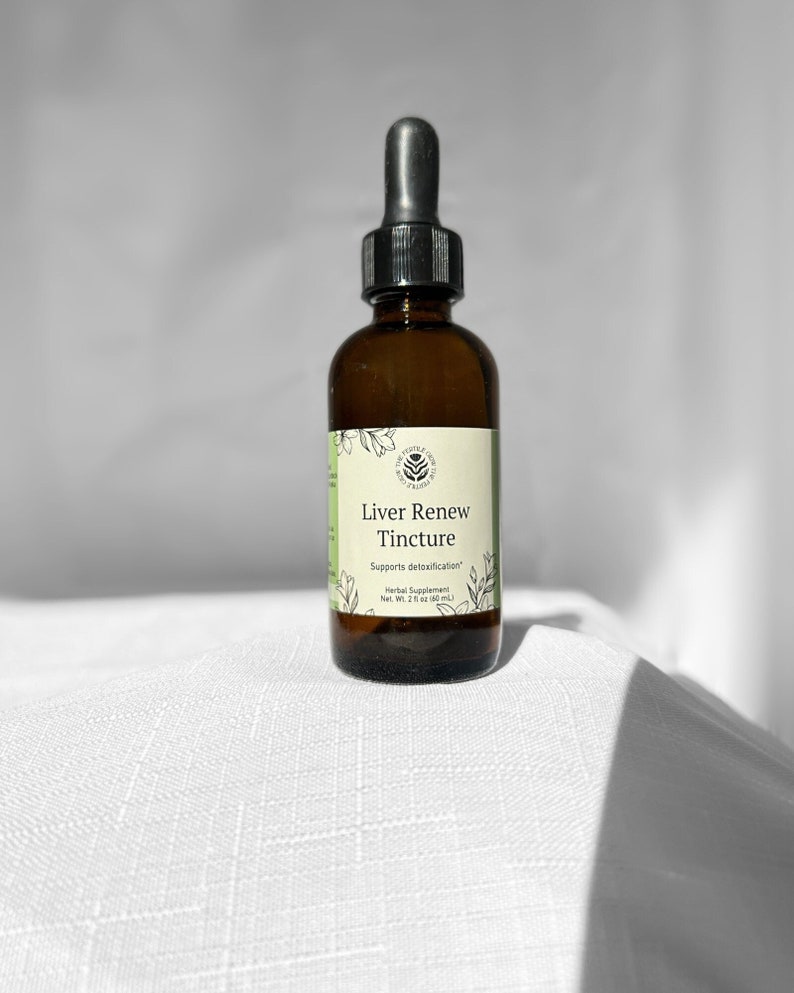 May include: A brown glass bottle of Liver Renew Tincture with a black dropper. The label is light green with black text and botanical illustrations. The bottle is on a white textured surface.