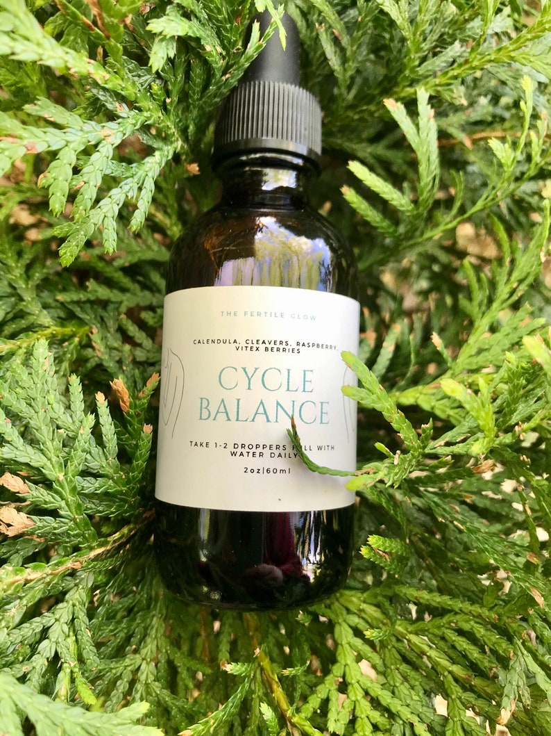 K&ouml;nnte beinhalten: Eine dunkelbraune Glasflasche mit schwarzer Pipette, beschriftet mit "CYCLE BALANCE" mit dem Text "TAKE 1-2 DROPPERS FILL WITH WATER DAILY" und "2oz|60ml". Die Flasche ist von gr&uuml;nem Laub umgeben.