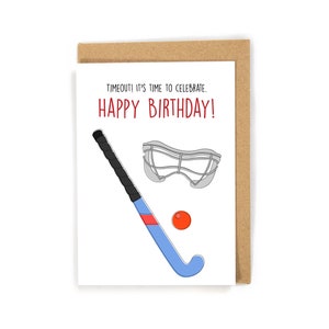 May include: A white card with the text "TIMEOUT! IT'S TIME TO CELEBRATE. HAPPY BIRTHDAY!" in red and black. A blue and black field hockey stick, a gray goalie mask, and a red ball are illustrated on the card.