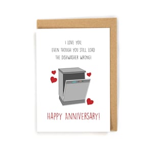 May include: A white card with a humorous anniversary greeting. The card features a cartoon dishwasher with an open door and red hearts. The text reads "I love you, even though you still load the dishwasher wrong! Happy Anniversary!"